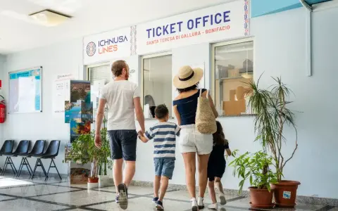 Famiglia in coda all'ufficio biglietti per la Corsica con bambini, pronti per l'avventura.