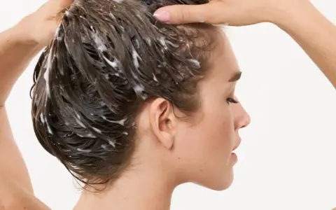 Frau wäscht sich die Haare, Schaum im Haar deutet auf die pflegende panthenol wirkung hin.