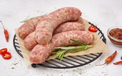 Surowa biała kiełbasa na ruszcie z rozmarynem, papryczkami chili i sosem. Dowiedz się, ile gotować białą kiełbasę, by była idealna.