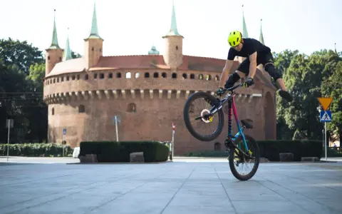 Kraków rowerem: kaskader na rowerze wykonuje akrobację przed Barbakanem.
