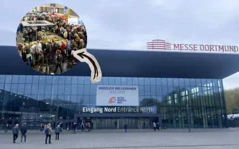 Besucher strömen zur Intermodellbau Messe in Dortmund. Ein kleiner Kreis zeigt die belebte Halle mit vielen Ausstellungsstücken.