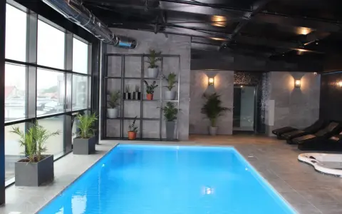 Nowoczesny hotel spa Białystok z basenem, jacuzzi i leżakami. Duże okna z widokiem na miasto.