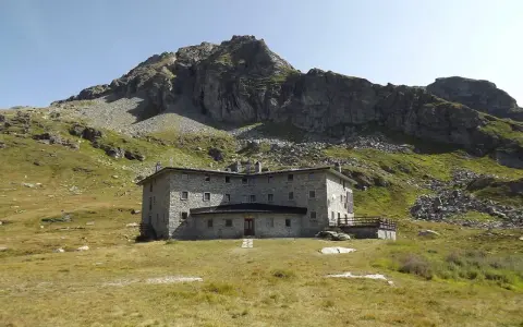 Un imponente rifugio in pietra, incastonato tra prati verdi e rocce imponenti, domina il paesaggio alpino. Un luogo ideale per chi cerca avventura e tranquillità nel cuore della Valle d'Aosta.