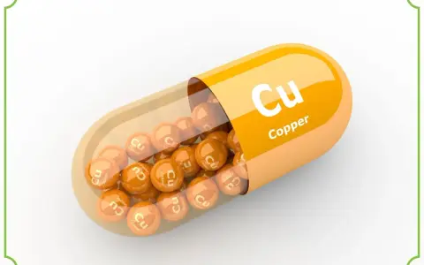 Pomarańczowa kapsułka z wysypującymi się z niej kulkami z napisem "Cu Copper". Suplement diety.