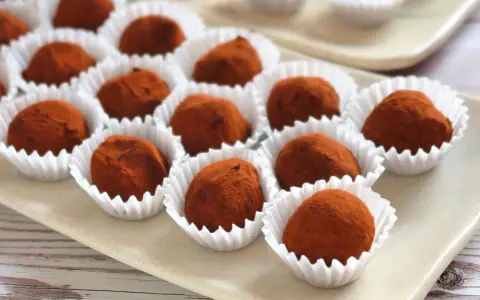 Deliciosas trufas de chocolate cubiertas de cacao, presentadas en sus envoltorios blancos.