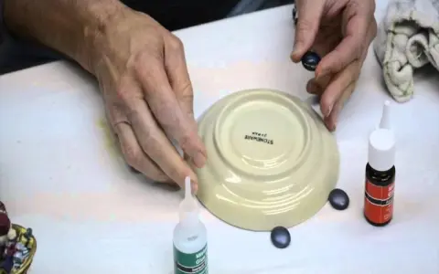 Mani che lavorano per riparare la ceramica con colla e piccoli pezzi.