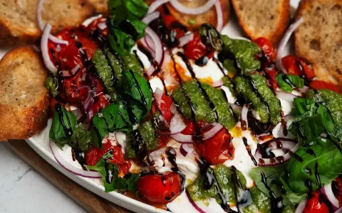 En krämig burrata med tomater, rödlök, basilika och pesto. Perfekt tillbehör till grillat bröd. Ett enkelt burrata recept.