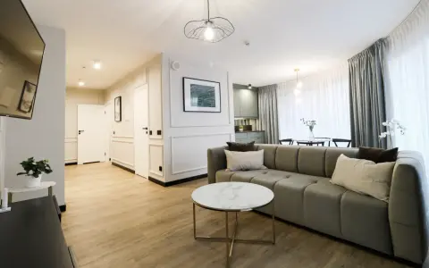 Nowoczesny apartament suite, z wygodną kanapą, stolikiem kawowym i widokiem na kuchnię.