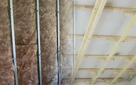 Isolierung in Metallständerwerk, bereit für das Kleben von Rigipsplatten. Decke mit Holzsparren und Dämmung.