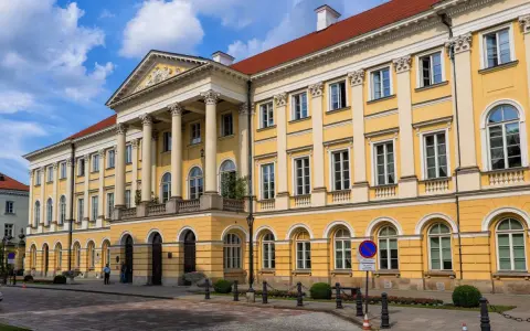 Imponujący żółty budynek z kolumnami, jeden z wielu **uczelni publicznych w Warszawie**.