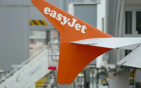 Pomarańczowe usterzenie EasyJet z białym logo, gotowe do lotu. Sprawdź wymiary bagażu podręcznego przed podróżą.