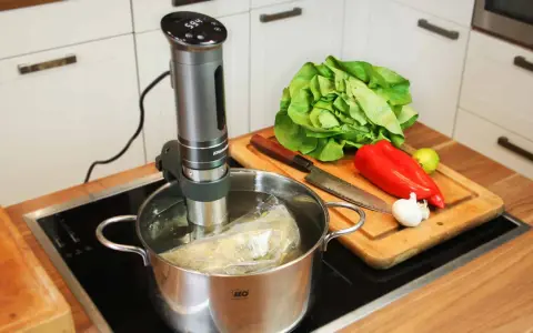 Sous vide garen: Ein Stab im Wasserbad, daneben frisches Gemüse auf einem Holzbrett. Perfekt für zarte Ergebnisse.
