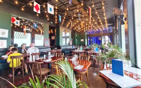 Ambiance marine dans un des restaurants de Saint-Malo. Drapeaux nautiques, lumières tamisées et tables dressées pour un repas convivial.