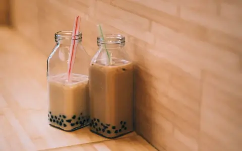 Två flaskor med boba, en populär dryck i Stockholm, står på ett träbord.