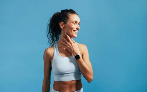 Donna sorridente con orologio sportivo, tocca il collo. Nonostante la sensazione di correre con la febbre, il suo sguardo è positivo.