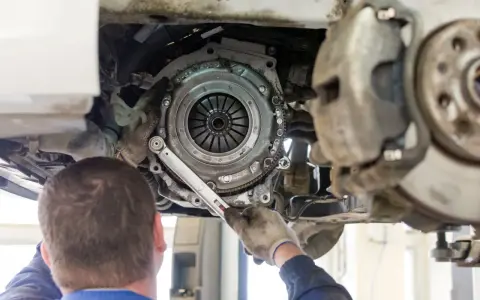 Mechanik dokręca śruby docisku sprzęgła. Wymiana sprzęgła krok po kroku w trakcie naprawy samochodu.