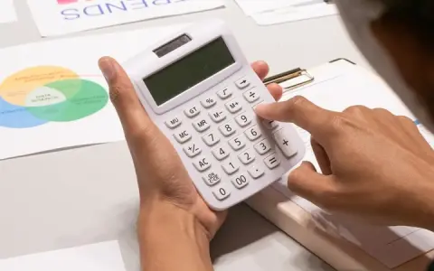 Persona calculando con calculadora blanca, rodeada de gráficos de tendencias y diagramas de Venn, analizando datos para gestionar masas patrimoniales.