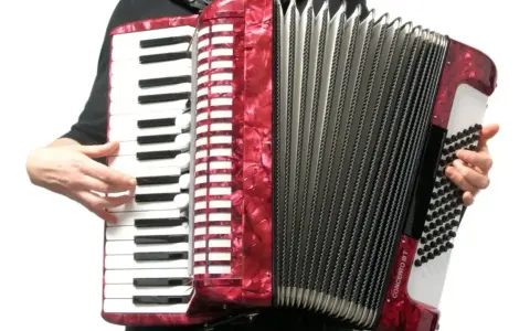 Ręce grają na czerwonym akordeonie, wydobywając dźwięki tego wspaniałego instrumentu.