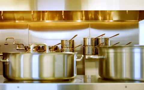 Une cuisine professionnelle avec des casseroles en acier inox 18/10 étincelantes. Des robinets chromés et des gicleurs de sécurité complètent l'ensemble.