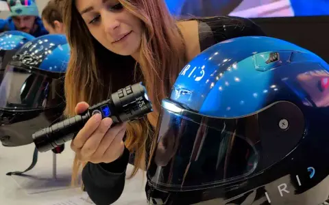 Donna mostra un casco da moto blu con visiera, evidenziando la sua importanza per la sicurezza. È bene che il casco sia dotato di visiera.