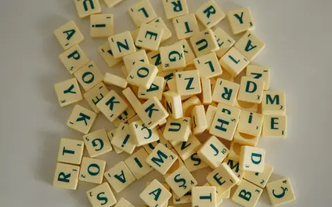 Fichas de letras de un juego de mesa, como las del Scrabble, dispersas. Cada ficha tiene una letra y un número. Un ejemplo visual de la diferencia entre lengua e idioma.