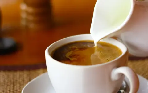 Mleko wlewane do kawy. Zastanawiasz się, ile kalorii ma kawa z mlekiem? To zależy od ilości i rodzaju mleka.
