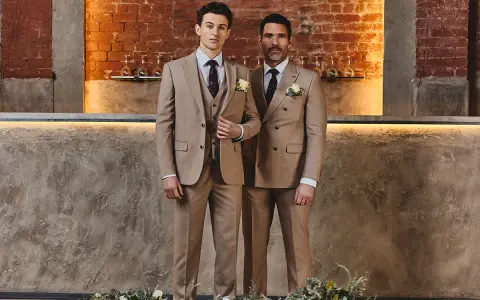 Two men in tan suits stand side-by-side. The man on the left wears a single-breasted suit, while the man on the right wears a double-breasted suit.