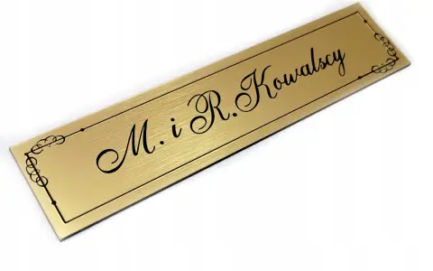 Elegancki, złoty szyld z napisem "M. i R. Kowalscy" w ozdobnej ramce.