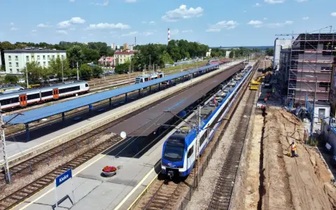 Widok z góry na dworzec kolejowy w Kielcach z pociągami na torach i placem budowy.