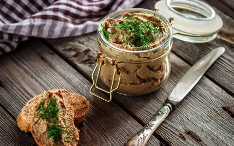 Un tarro de rillettes, paté de cerdo desmenuzado, con eneldo fresco, servido sobre pan tostado.