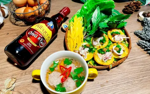 Bouteille de sauce poisson asiatique Phu Quoc, plat de crêpes garnies de calamars et de légumes, et un bol de boulettes.