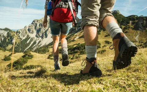 Dobre buty w góry latem to podstawa. Para wędrowców w solidnych trekkingowych butach i skarpetach pokonuje górski szlak.
