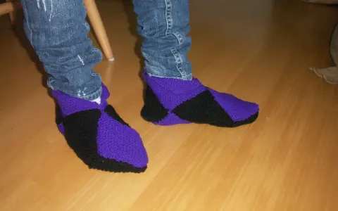 Ett par stickade innetofflor i lila och svart, med jeans till. Perfekta för mysiga hemmakvällar.