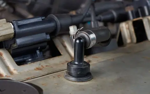 A black rubber PCV valve hose connected to a metal engine component. This part can cause bad PCV valve symptoms if it fails.