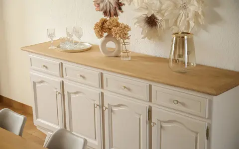 Buffet année 30 repeint, avec un plateau en bois clair. Des verres et un vase décorent le dessus.