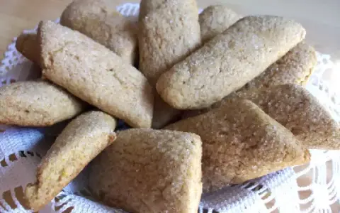 Un cesto pieno di biscotti della nonna, dorati e cosparsi di zucchero, invitano a un assaggio di dolcezza casalinga.
