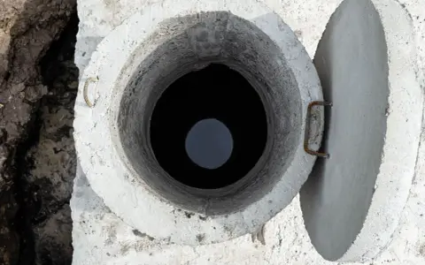 Otwarty betonowy właz szamba, widok z góry. Rozważasz, jak uszczelnić szambo betonowe od środka?