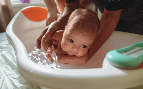 Delikatne kąpiel noworodka w wanience. Czy przy gorączce można kąpać dziecko? Tak, ale w letniej wodzie.