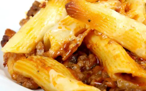 Macarrones con carne y queso fundido, cubiertos con salsa de tomate.