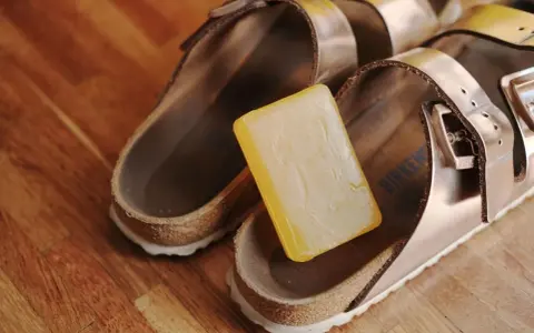 Kostka mydła obok sandałów Birkenstock, gotowa do czyszczenia.
