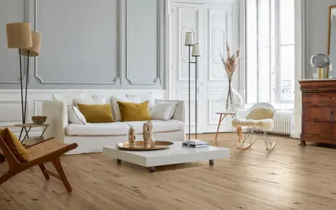 Stilvolles Wohnzimmer mit hellem Parkettboden, der durch regelmäßige Parkett Pflege glänzt. Gemütliche Couch, Sessel und ein moderner Couchtisch.