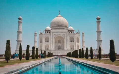 El Taj Mahal, en Agra, India, se alza majestuoso con su cúpula blanca y minaretes, reflejado en el estanque.