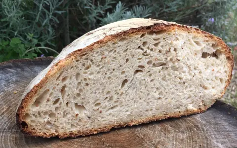 Une mie aérée et une croûte dorée pour ce pain au levain rapide, posé sur une tranche de bois.