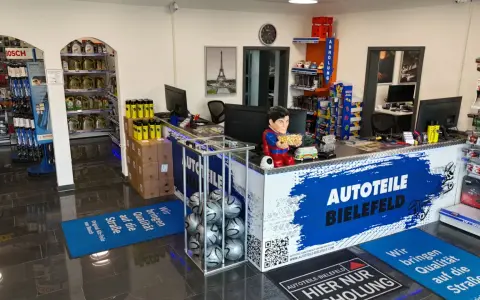 Autoteile-Shop mit Theke, Regalen voller Autoteile, einem Superman-Aufsteller und Fußmatten.