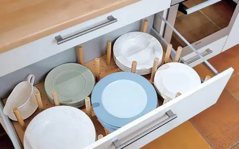 Schubladen organizer selber machen: Teller und eine Soßenkanne ordentlich in einer Auszugschublade verstaut, dank Holzstäbchen.