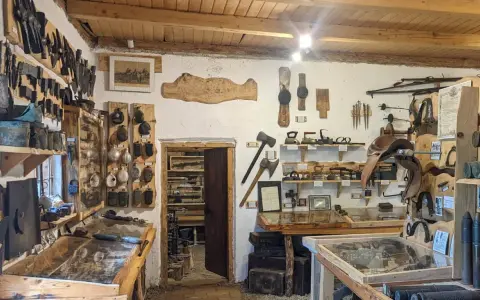 Wnętrze muzeum historii Bieszczad. Eksponaty to narzędzia, broń, siodła i przedmioty codziennego użytku.