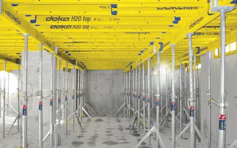 Sistema de apeo estructural Doka H20 top, con puntales metálicos y vigas amarillas, listo para soportar una losa.