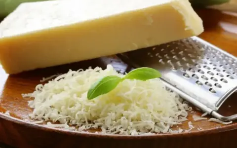 Tarty parmezan z bazylią i tarką. Czy parmezan jest wegetariański? Tradycyjnie nie, bo zawiera podpuszczkę zwierzęcą.