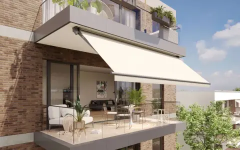 Balcón moderno con sofá, mesa y sillas, protegido por uno de los tipos de toldos más elegantes.