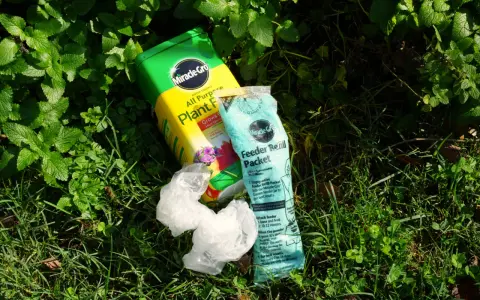 Miracle-Gro plant food and feeder refill packet lie on grass. While not inherently toxic, proper use is key to avoid harming plants.